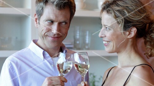Man and woman clinking glasses of white wine