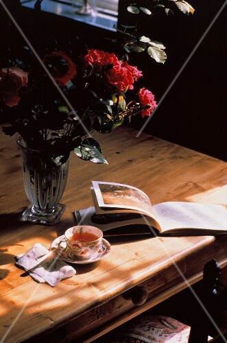 A Cup of Tea on a Table with a Book and Flowers