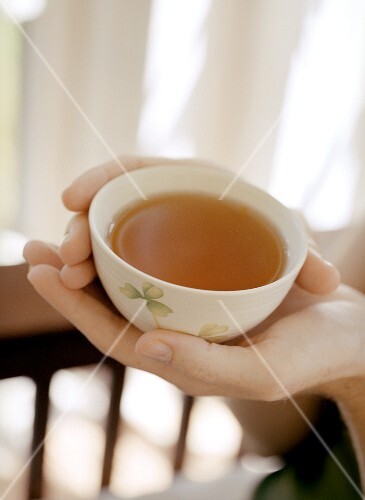 Hands holding bowl of tea