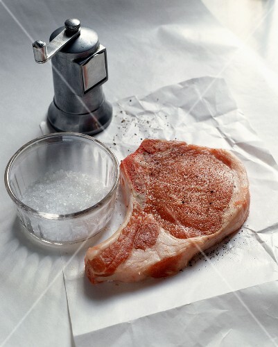 A Raw Pork Chop with Salt and Pepper