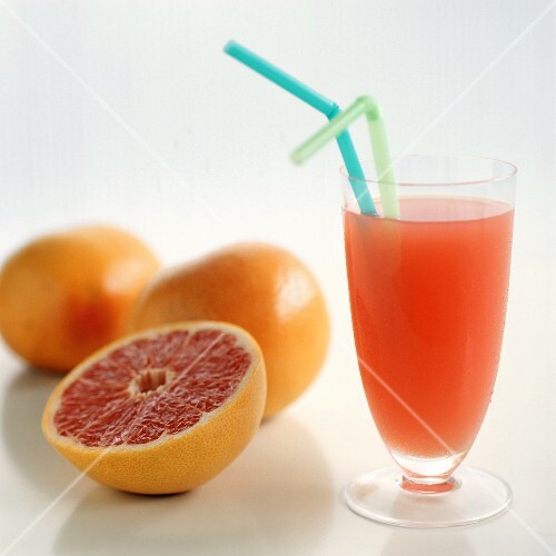 Glass of pink grapefruit juice beside fresh grapefruits
