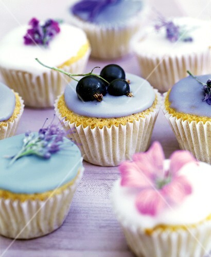 Muffins mit verschiedenem Zuckerguss und Blüten verziert