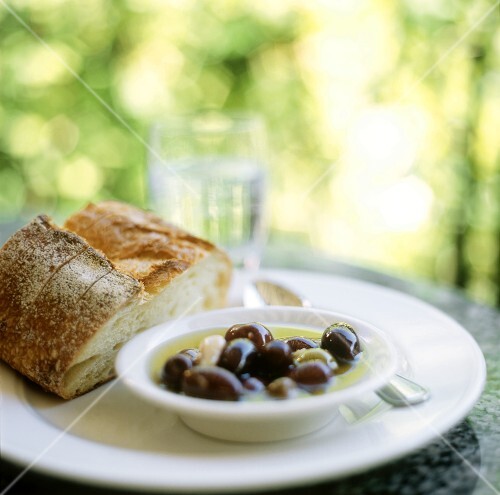Marinated olives and white bread on table in open air
