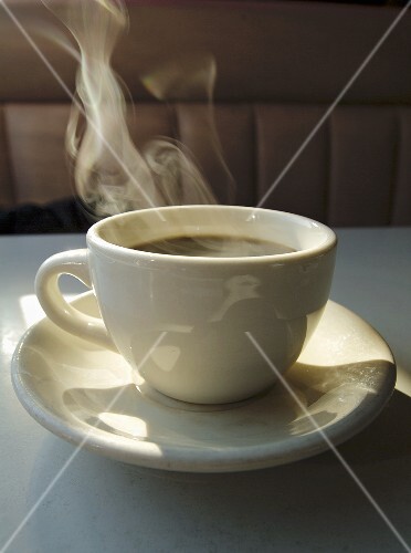 Dampfender schwarzer Kaffee in weisser Tasse