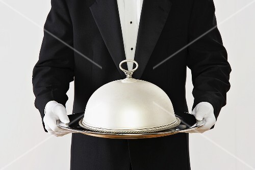 Butler hält Silbertablett mit Servierglocke