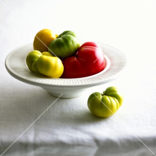 Bunte Heirloom Tomaten in und neben weisser Schale