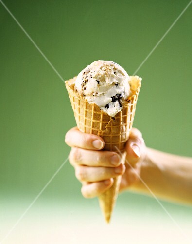 Hand Holding Waffle Cone with Cookie Dough Ice Cream