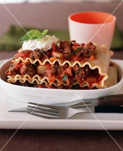 Serving of Ground Beef Lasagna in an Oval Dish; Fork and Knife