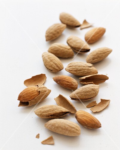 Many Whole and Shelled Almonds on a White Background