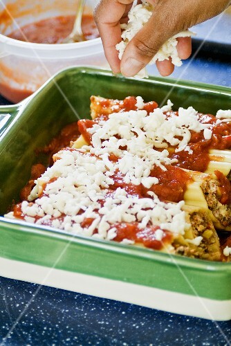 Hand Sprinkling Cheese on Stuffed Lasagna made with Tufoli