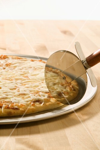 Pizza About to be Sliced with a Pizza Cutter