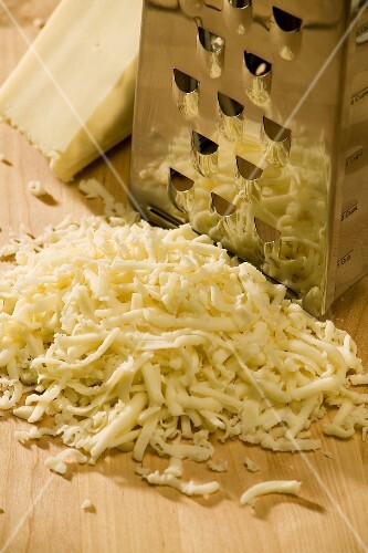 Shredded Cheese Next to a Metal Box Grater