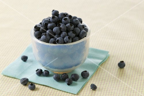 Small Bowl of Blueberries with Blueberries Around the Bowl