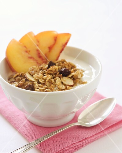 Bowl of Yogurt Topped with Granola and Sliced Peaches