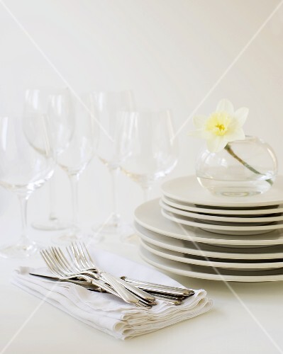 Stack of White Plates with White Napkins, Flatware and Glasses
