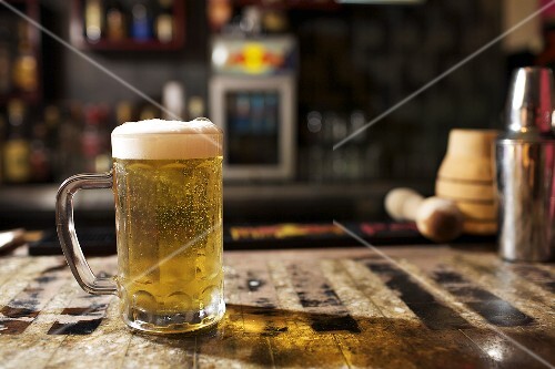 Glass of Beer with Foam on Bar Counter