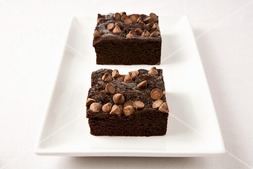 Two Brownies Topped with Chocolate Chips on a White Dish