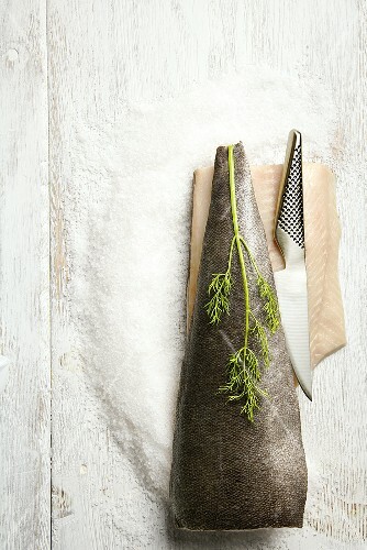 Cod on a Pile of Salt with a Sushi Knife; On White Wooden Table